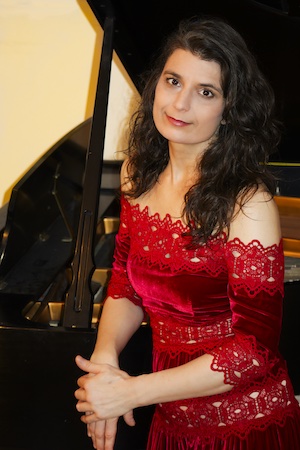 Mira Armij Gill wearing a red dress, leaning against a piano.; Guest Artist Masterclass: Mira Armij Gill, piano