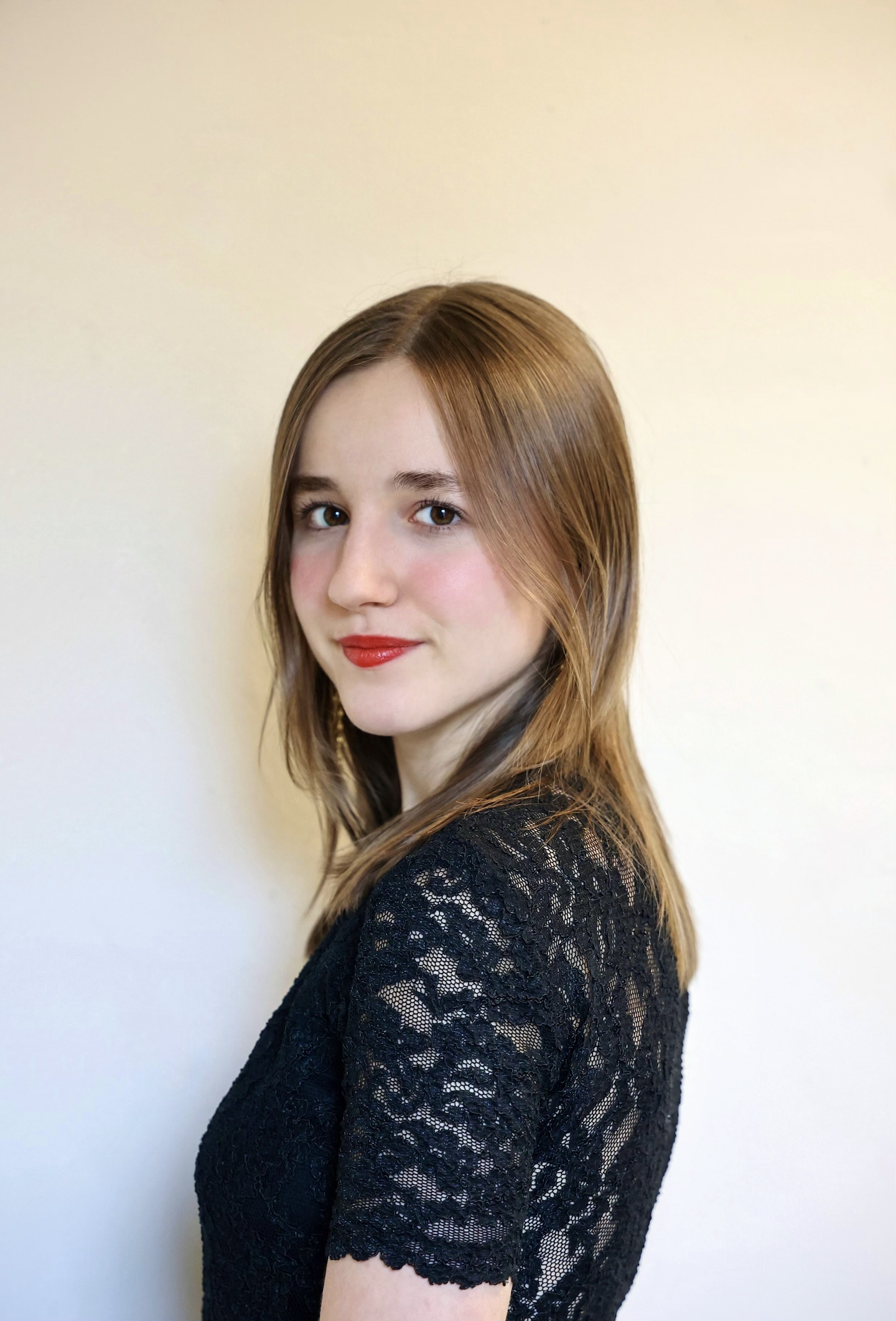 Juliette Benveniste looking at the camera, wearing a black short sleeve lace top and red lipstick. ; Third Year Recital