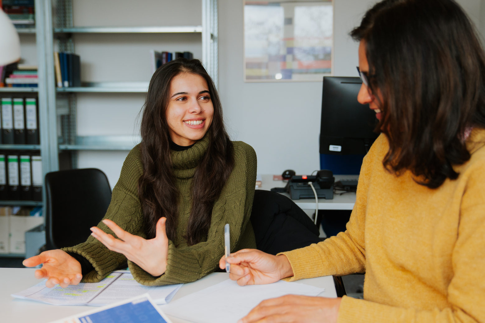 A student and professor discuss with each other and take notes seated at a seminar table.; Spring Transfer Application Deadline