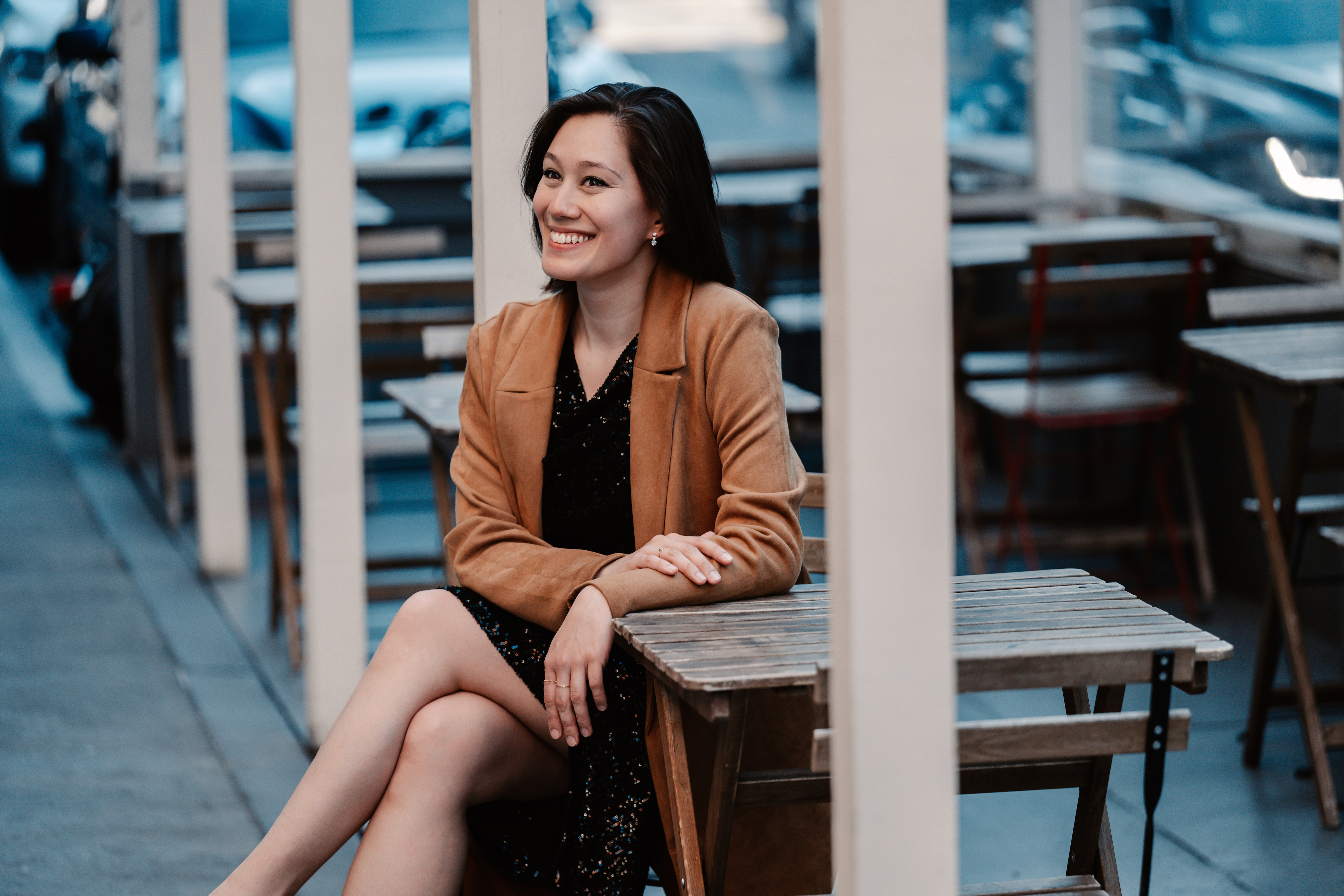 Sun-Ly Pierce sitting at a cafe table, wearing a dress and a long suede coat.; Alumni/ae Spotlight: Sun-Ly Pierce, mezzo-soprano, with Kayo Iwama, piano