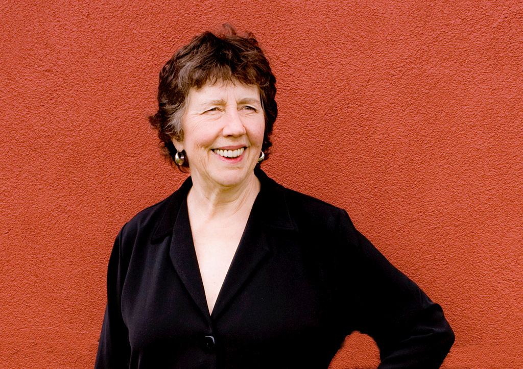 Joan Tower smiling against a solid red wall. ; Celebration:&nbsp;A Concert honoring Joan Tower's 54th year at Bard, "My longtime home"