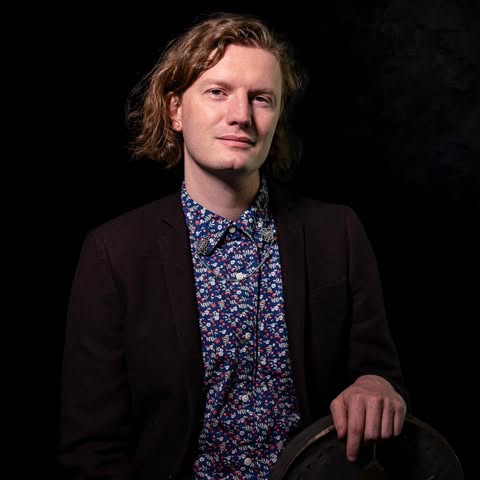 A piano on an empty stage.; Michael Jones, percussion