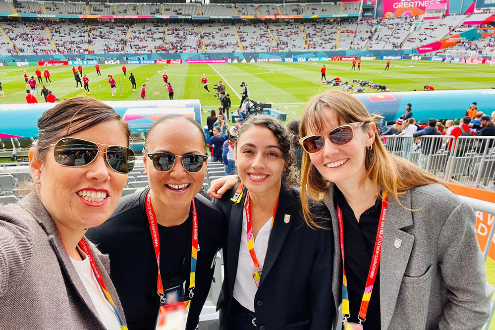 Diplomatic Security Service Special Agent Stephanie Harris ’08 CCS ’13 (far right) protects the US Women’s National Team at the FIFA Women’s World Cup. Above, Harris posed with other DSS special agents and a security liaison officer from the New Zealand Police at the first Team USA match against Vietnam at Eden Park Stadium in Auckland, NZ, July 22, 2023. Photo courtesy of US Department of State