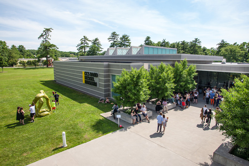 Exterior shot of the Center for Curatorial Studies, Bard College: a large, metal building surrounded by green grass and trees. People walk around on a concrete patio near the entrance.
; CCS Bard to Double Capacity of Library and Archives&nbsp;with New Keith Haring Wing