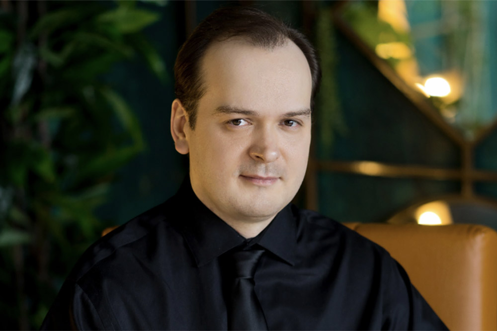 a man in a black shirt looks at the viewer