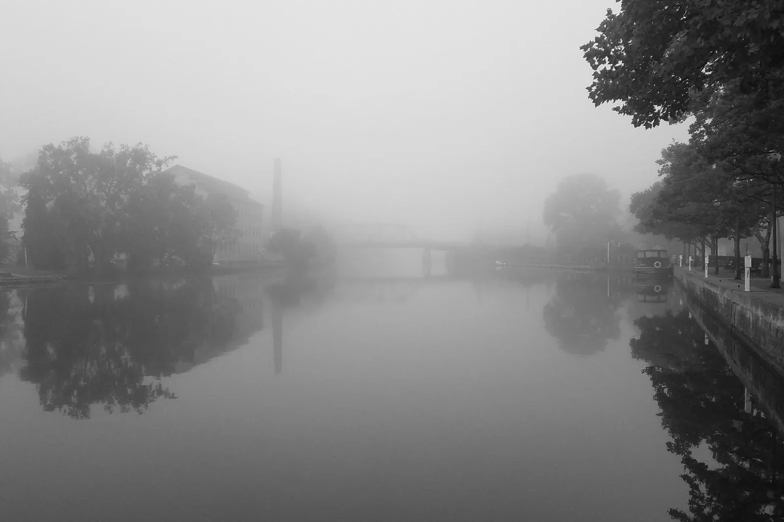 A black and white photo of a foggy river.