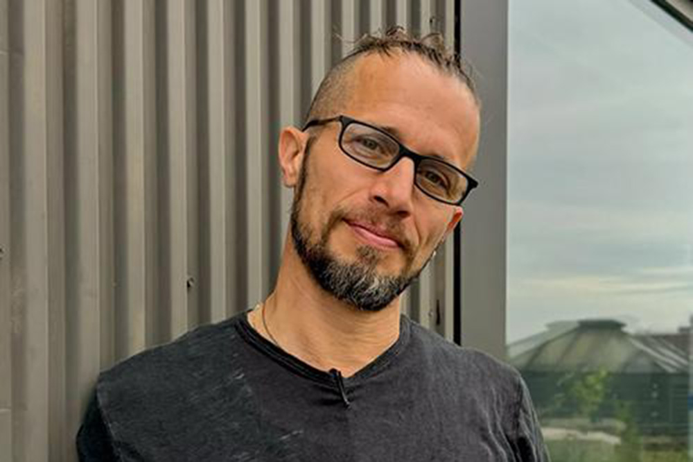 a man in glasses and a gray shirt looks out at the viewer