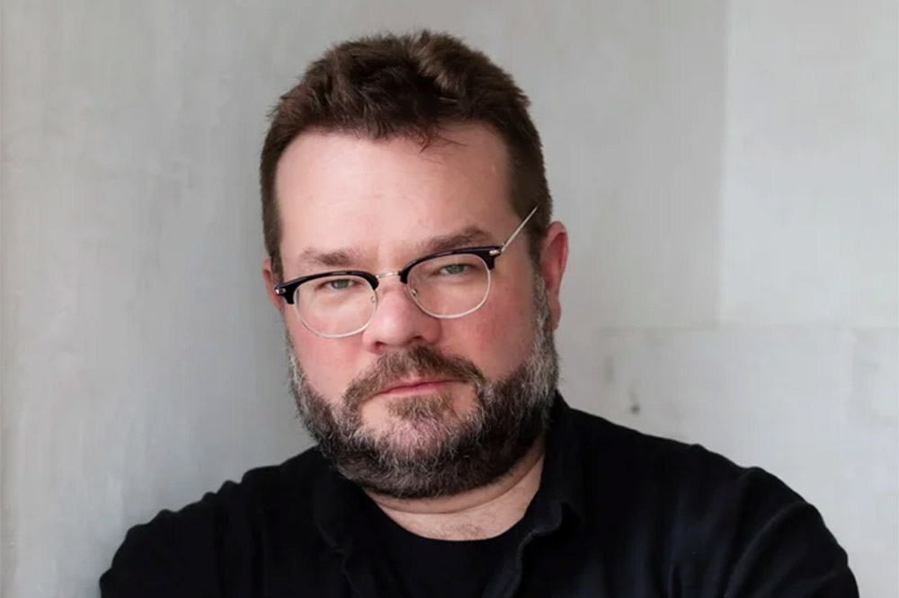 a man in glasses looks at the viewer