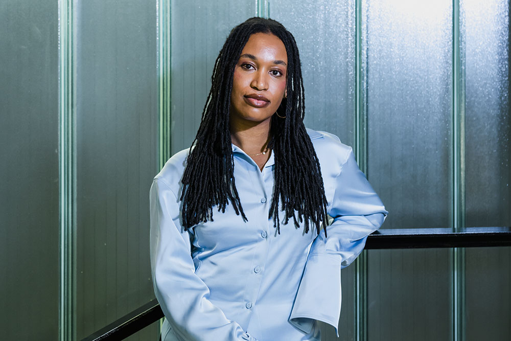 Tschabalala Self in front of a blue background looking at the camera.