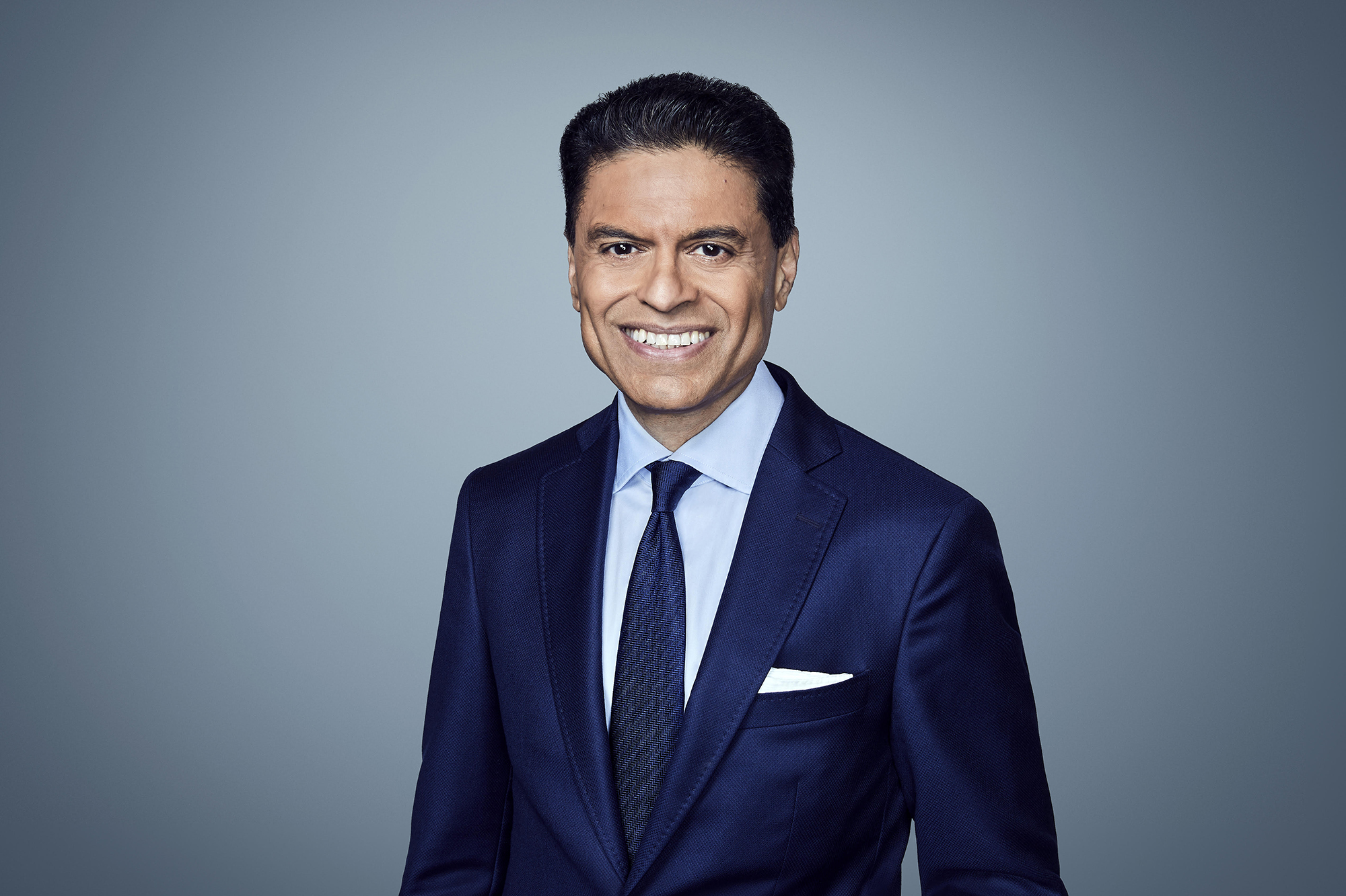 a man in a blue suit smiles at the viewer