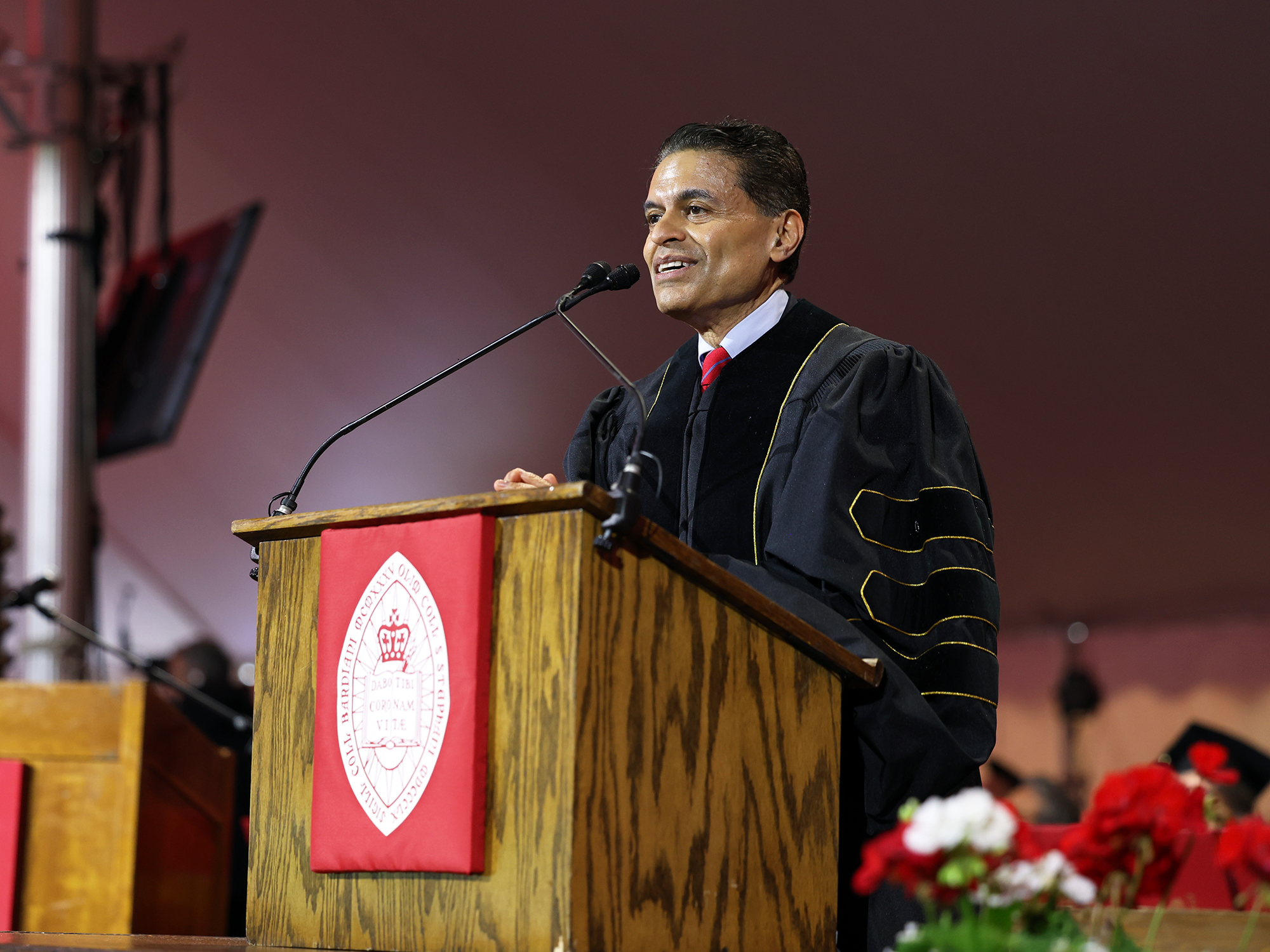 a man stands at a podium in academic dress