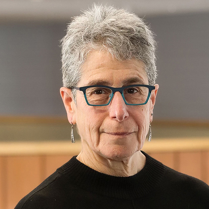 a woman with short gray hair and glasses smiles at the viewer