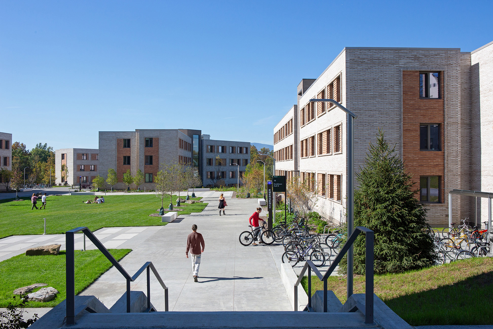 a view of a campus with students, lush grass, and mountain views
