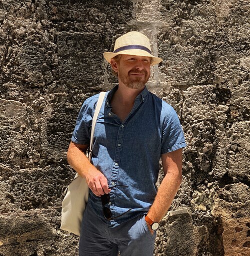 Arlo Haskell &rsquo;00 in a hat standing next to a large rock.
