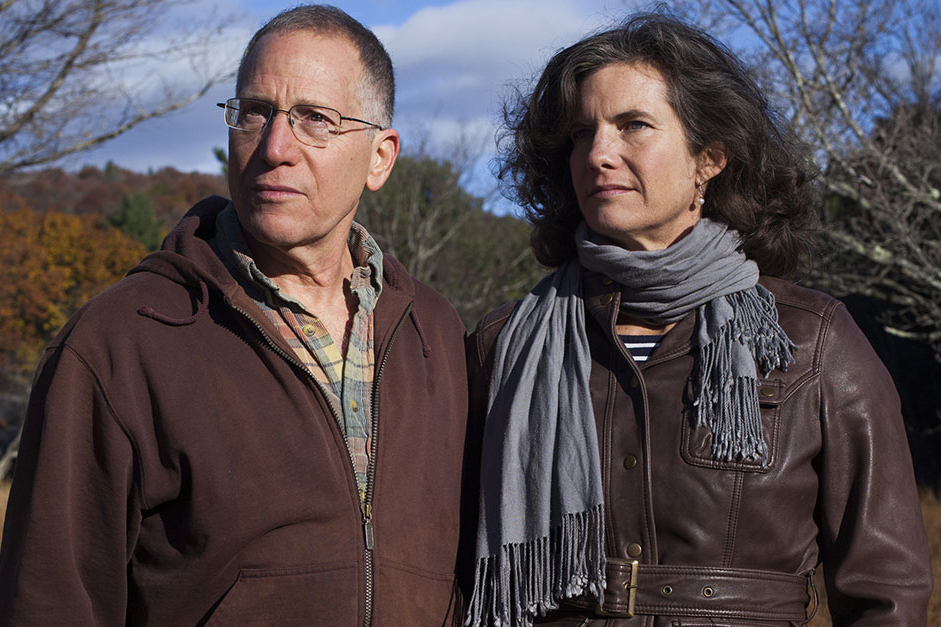 Richard Ostfeld and Felicia Keesing stand together before a line of trees in autumn.