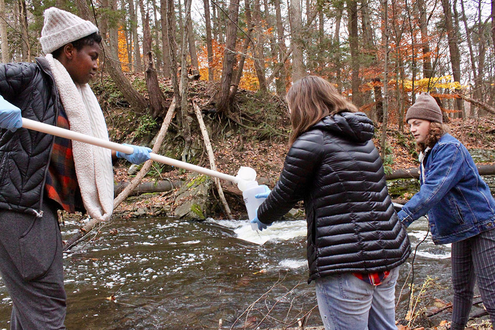 Students gather water samples from a creek in autumn