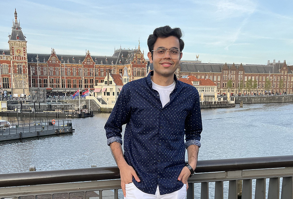 A student stands in front of a river with a row of buildings behind him.; Get Engaged Alumni Speaker Series: The Essentials of Effective Pitching
