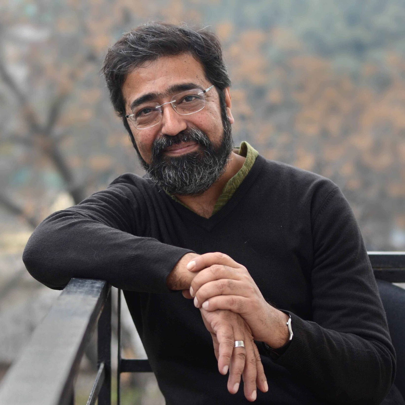 A man with a beard and glasses smiles at the camera. There are trees with orange leaves behind him.; Visit https://bard.zoom.us/webinar/register/WN_d6WSOBKkRwerqgIE3zcKWg