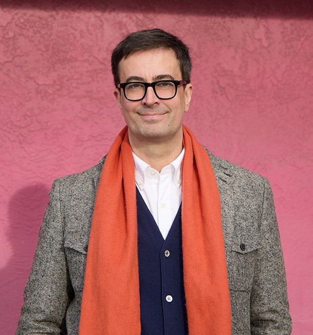 Joel Whitney, a man in a jacket and orange scarf, smiling faintly at the camera.; Literary Radicals: How Literature and Politics Have Shaped Our World