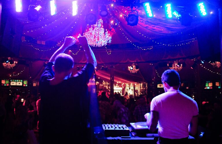 A DJ playing music in a lighted tent.; After Hours at the Spiegeltent