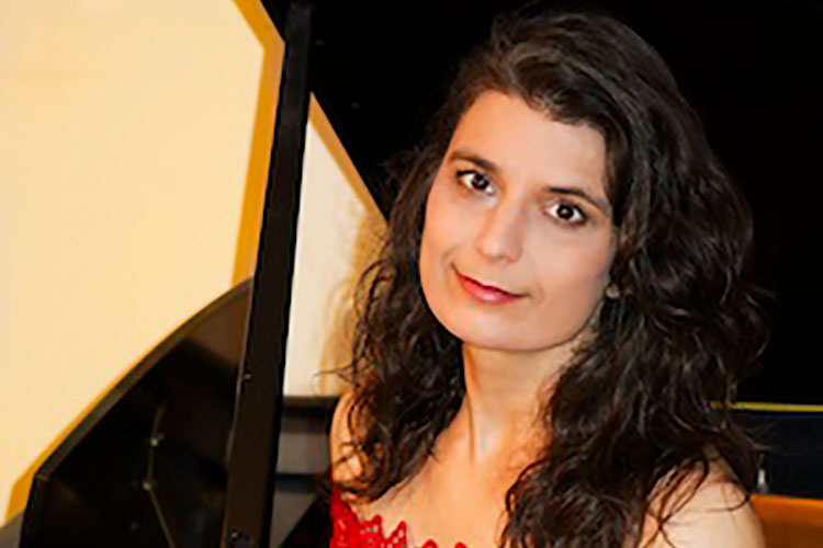 Mira Armij Gill wearing a red dress, leaning against a piano.; Guest Artist Recital: Mira Armij Gill, piano&nbsp;