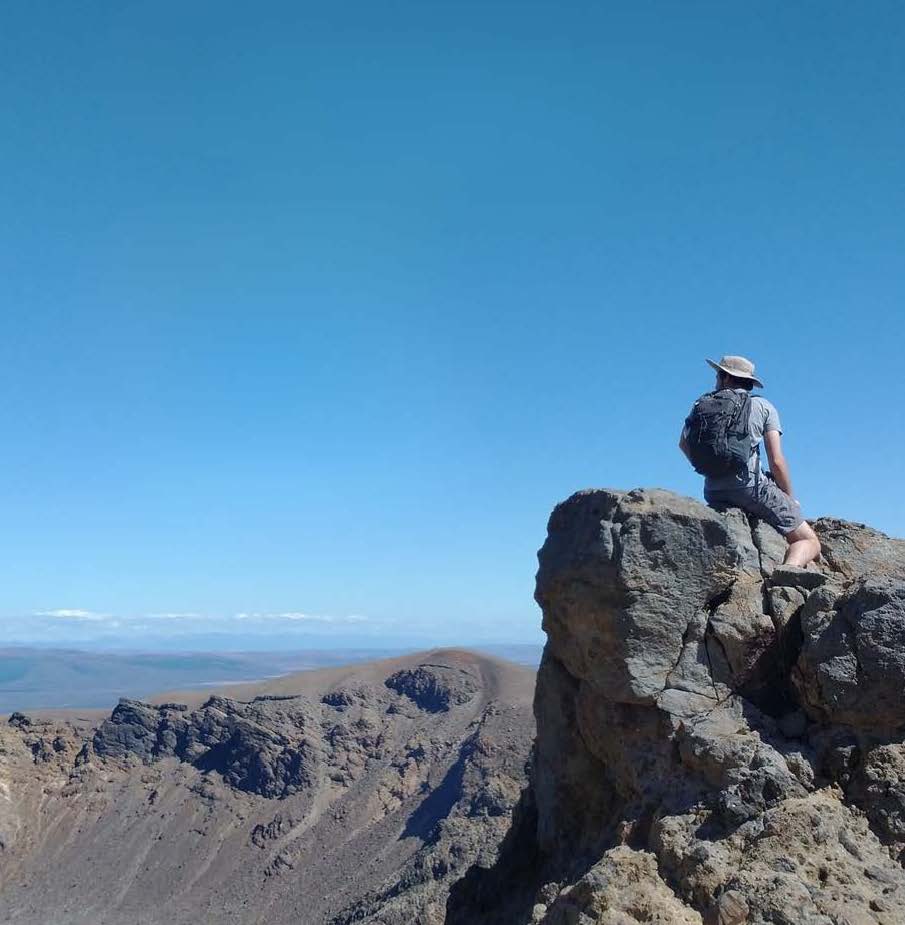 A hiker sitting on a rock, looking over a vast landscape.; Degree Recital:&nbsp;Ethan Young, cello