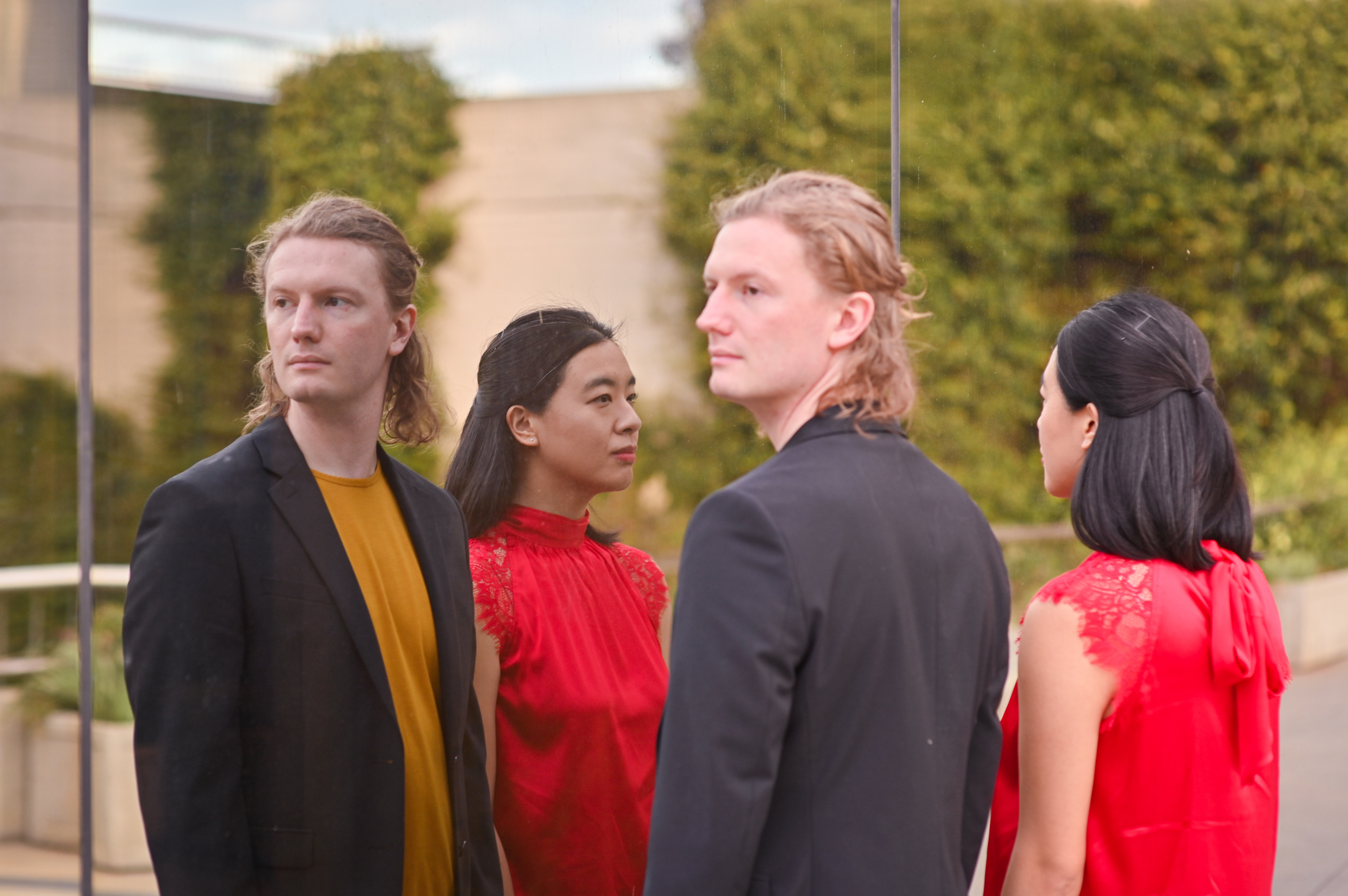 Michael Jones and Shaoai Ashley Zhang reflected in a mirror with greenery.; Duo Refracta