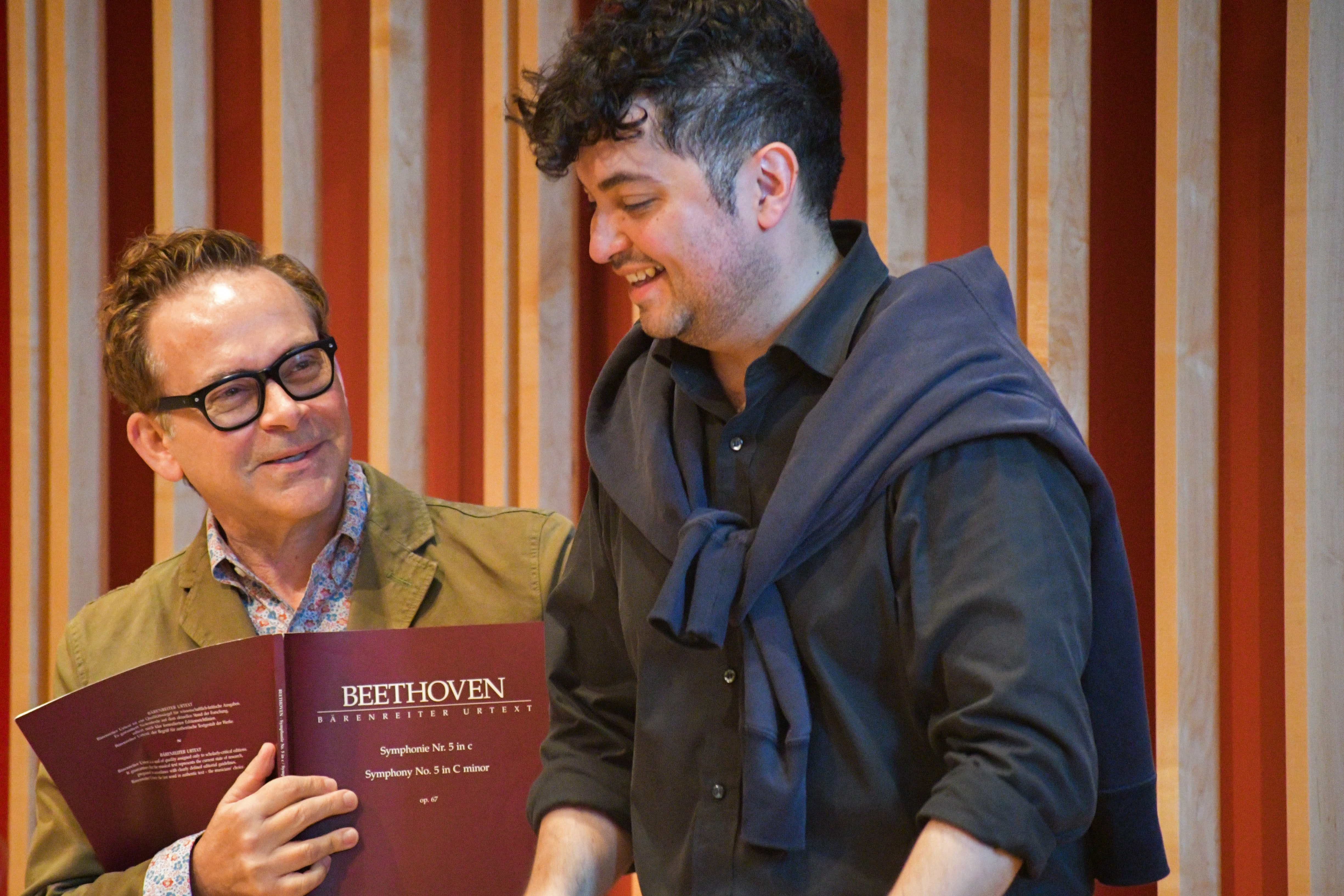 Two men talking over a book of Beethoven's sheet music.