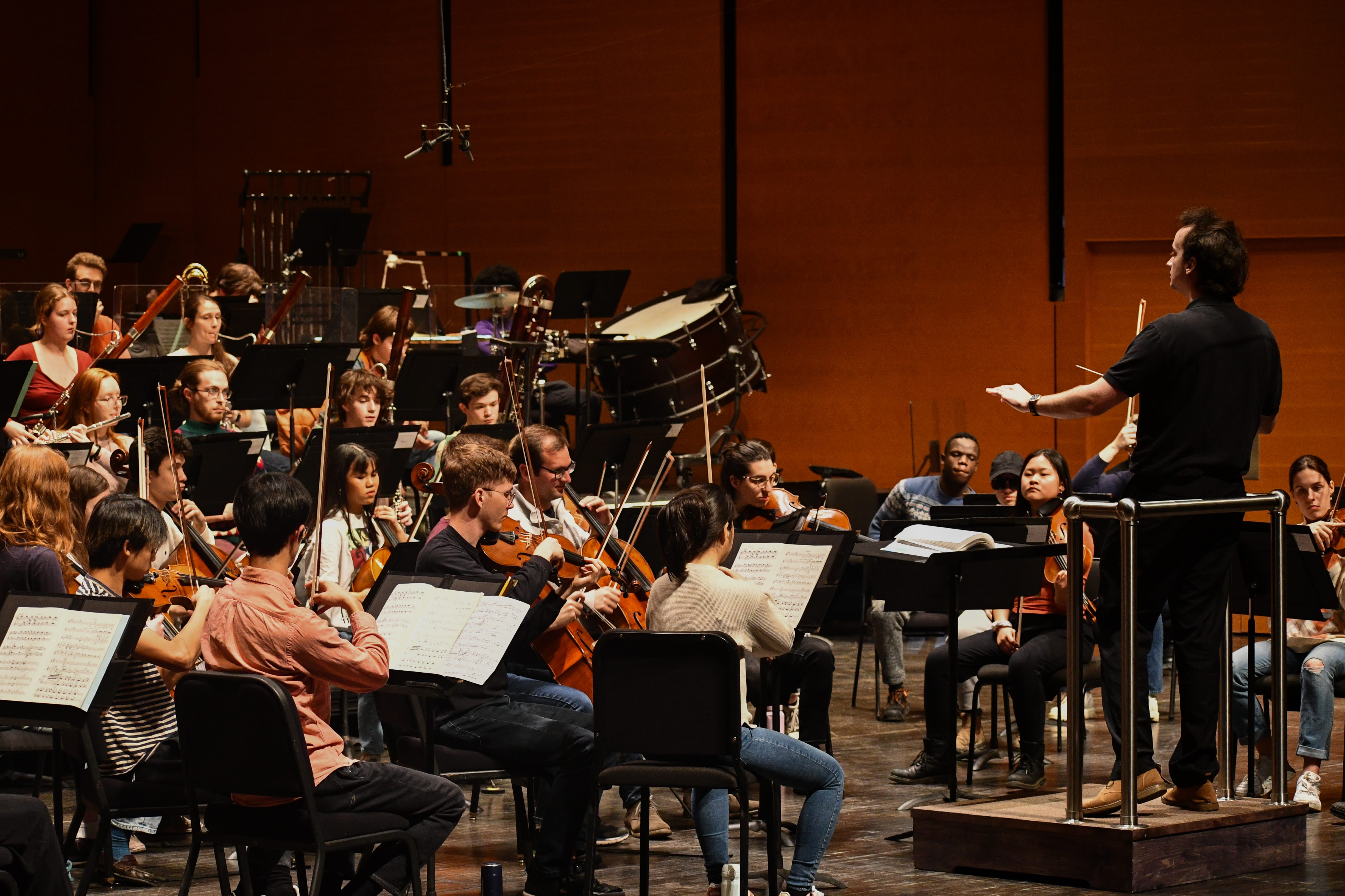 A student conducting a large orchestra.