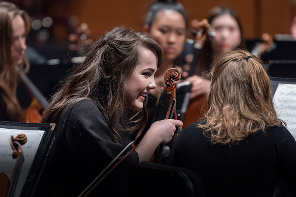 Musicians on a stage chat happily.