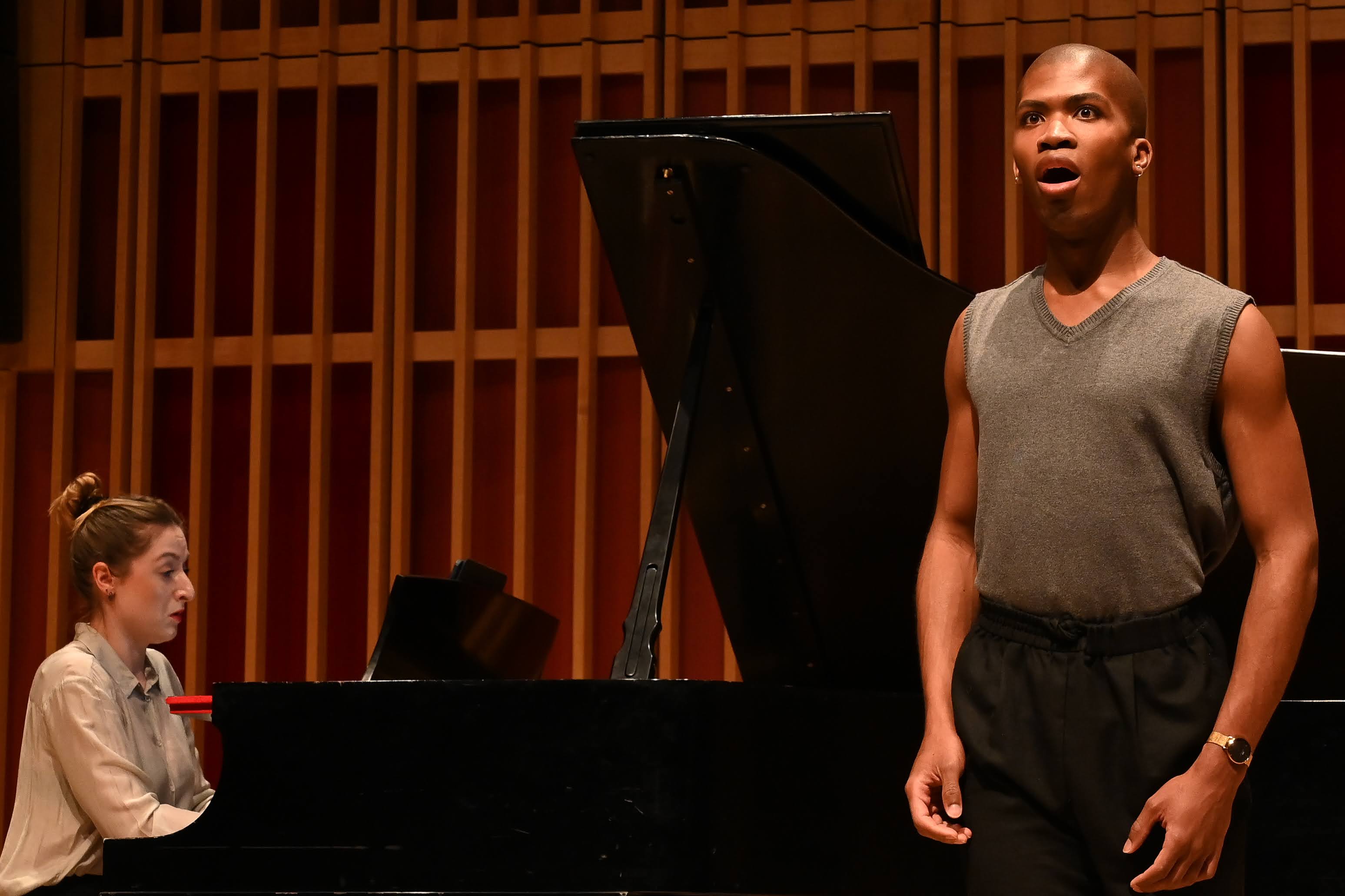 A singer performs with a pianist behind him.
