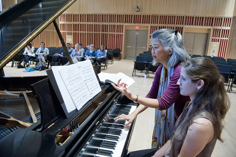 Kayo Iwama works with a student who is seated at the piano.